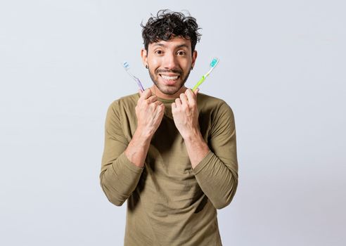 Handsome man holding two toothbrushes isolated. Smiling guy holding two toothbrushes isolated. Smiling people showing two toothbrushes isolated
