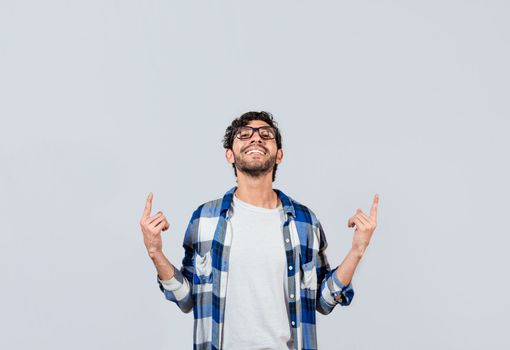 Smiling man in glasses pointing fingers up, People recommending something with fingers up isolated, Young man pointing an advertisement with fingers up