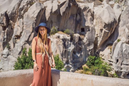 Young woman exploring valley with rock formations and fairy caves near Goreme in Cappadocia Turkey.