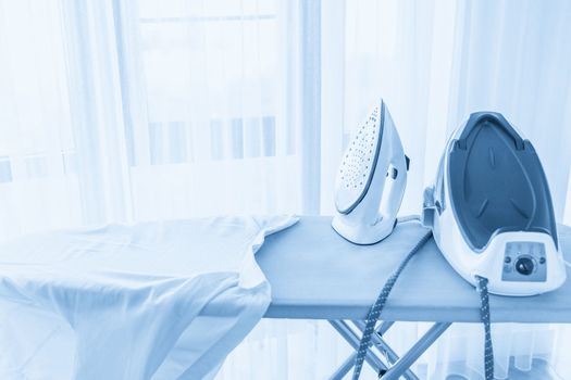 Steam generator iron standing on ironing board near panoramic window