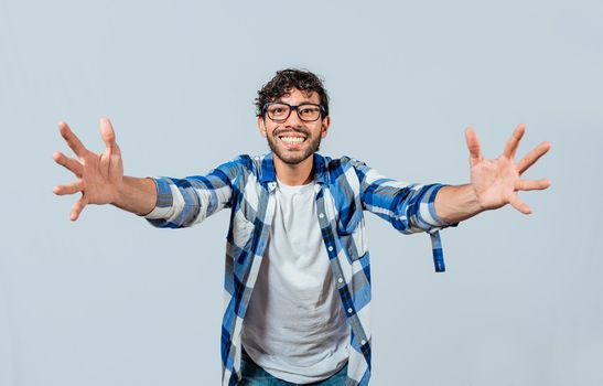 Man welcoming with open arms isolated. Friendly person welcoming. Generous young man with open arms isolated, Man sharing with open hands looking at the camera with a friendly smile