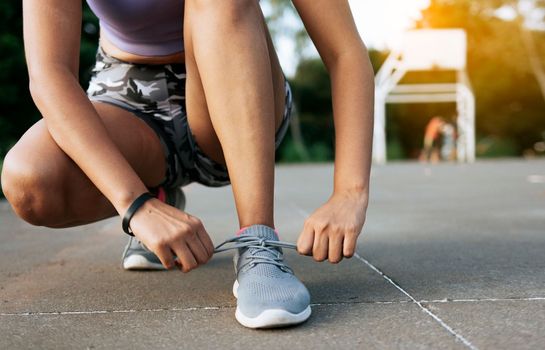 Sport girl tying her shoe laces in a park. Runner girl tying her running shoes in a park with space for text, Close-up of sporty woman tying her shoes with copy space