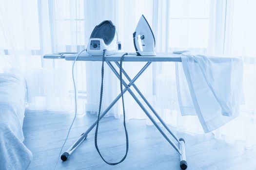 Steam generator iron standing on ironing board near panoramic window