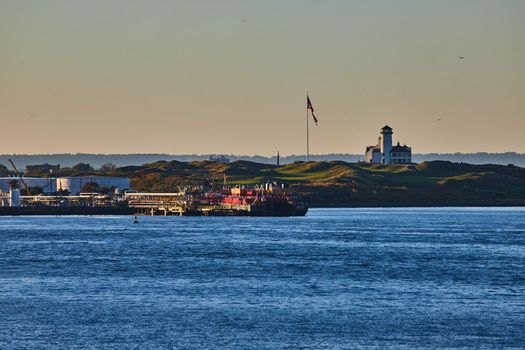 Image of Bayonne Golf Club with American Flag and industrial ships from ferry with soft golden light