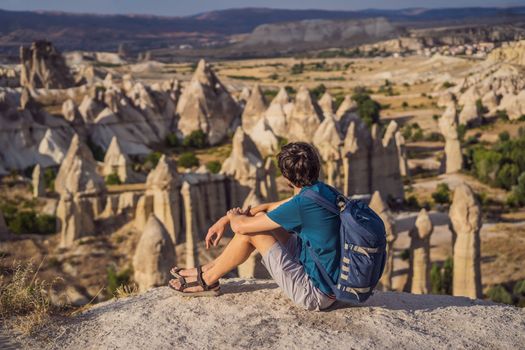 Young man exploring valley with rock formations and fairy caves near Goreme in Cappadocia Turkey.