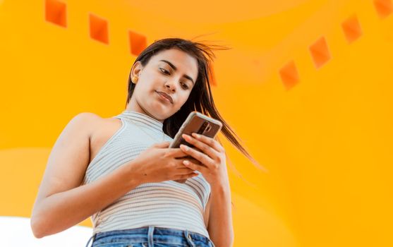 Portrait of attractive latin girl messaging on cell phone. Low angle of a beautiful Latin girl using the smart phone. Low angle of a young latin woman texting on cell phone