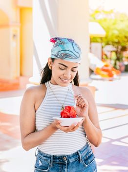 Young woman holding a cup of shaved ice on the street. Concept of a girl with a Nicaraguan raspado. Portrait of smiling girl holding shaved ice in the street. ICE SHAVING from Nagarote