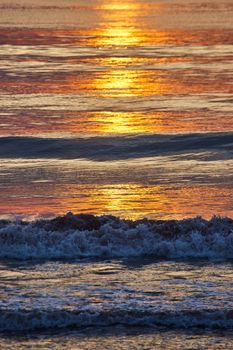 Image of Detail vertical of crashing waves over east coast ocean with golden sunrise light casting light