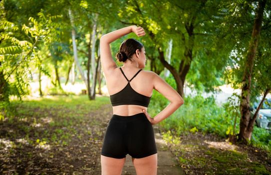 Sporty woman doing stretching exercises before running. Athlete girl stretching arms before running. Concept of physical activity and healthy life, Athlete girl doing warm-up exercises in a park