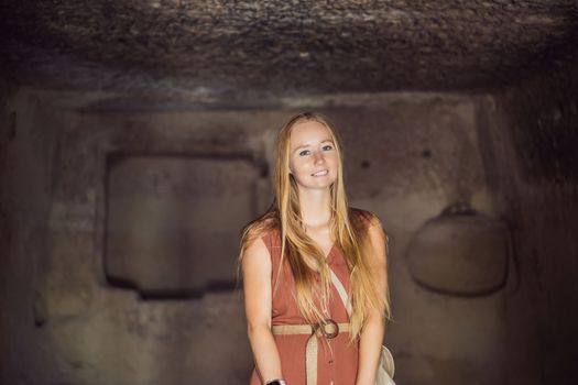 Young woman exploring valley with rock formations and fairy caves near Goreme in Cappadocia Turkey.