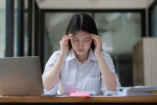 Stressed Asian business woman worry with many document on desk at office.