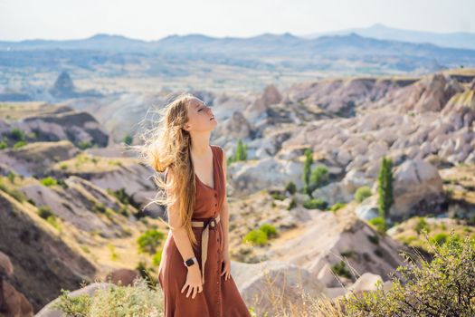 Young woman exploring valley with rock formations and fairy caves near Goreme in Cappadocia Turkey.