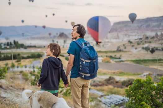 Tourists father and son looking at hot air balloons in Cappadocia, Turkey. Happy Travel in Turkey concept. father and son on a mountain top enjoying wonderful view.