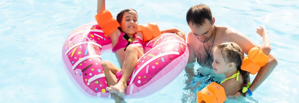 Happy family having fun on summer vacation, playing in swimming pool. Active healthy lifestyle concept.