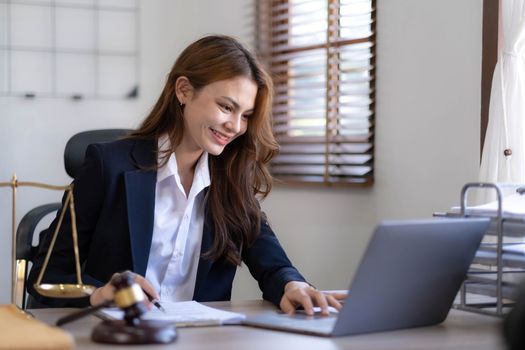 Attractive young lawyer in office Business woman and lawyers discussing contract papers with brass scale on wooden desk in office. Law, legal services, advice, Justice and real estate concept...