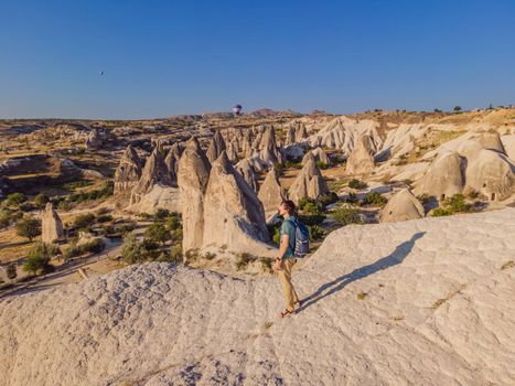 Young man exploring valley with rock formations and fairy caves near Goreme in Cappadocia Turkey.