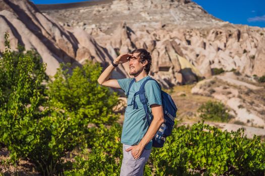 Young man exploring valley with rock formations and fairy caves near Goreme in Cappadocia Turkey.