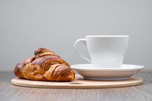 coffee and croissant on a wooden tray on the table. breakfast