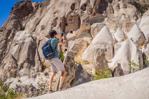 Young man exploring valley with rock formations and fairy caves near Goreme in Cappadocia Turkey.
