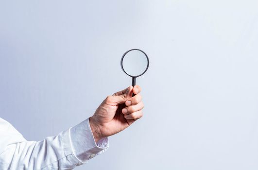 Man hand holding magnifying glass on white background. Hand holding magnifying glass looking for something with space for text, Hand holding magnifying glass on isolated background