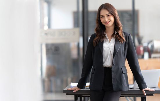 Charming Young Asian businesswoman standing in the office. Looking at camera...