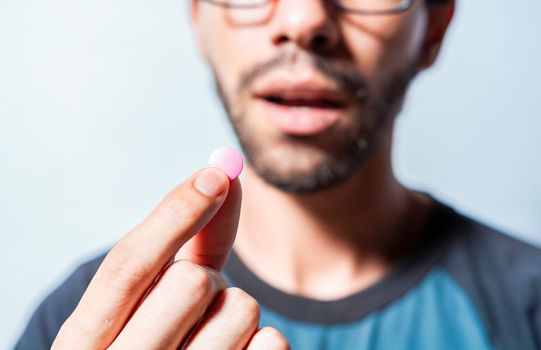 Close up of young man holding aspirine. Self-medication concept, Man putting a pill in his mouth isolated, Close-up of a man taking an aspirin, Person taking a pill isolated