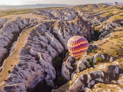 Colorful hot air balloons flying over at fairy chimneys valley in Nevsehir, Goreme, Cappadocia Turkey. Spectacular panoramic drone view of the underground city and ballooning tourism. High quality.