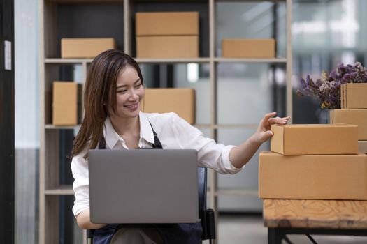 A portrait of a small startup, an SME owner, an Asian female entrepreneur checking orders to arrange the produce before packing the products in the inner boxes with the customers. Freelance concepts..