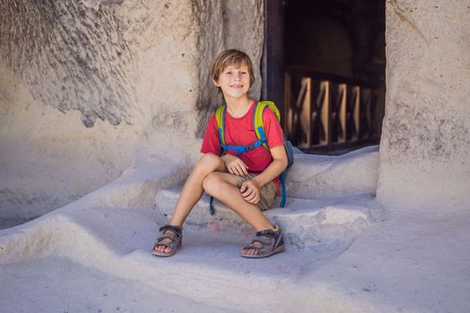 Boy tourist exploring valley with rock formations and fairy caves near Goreme in Cappadocia Turkey.