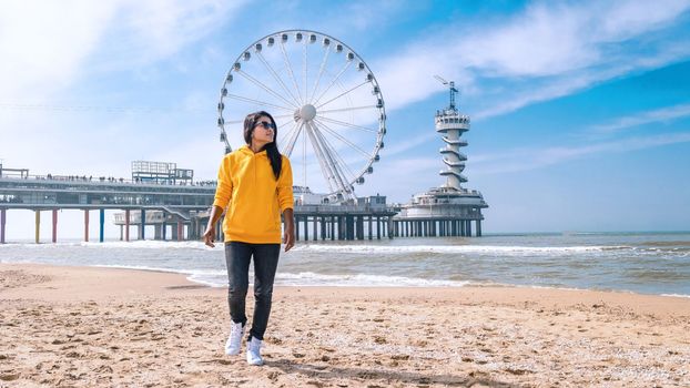 woman on the beach of Scheveningen Netherlands during Spring, The Ferris Wheel at The Pier at Scheveningen in the Netherlands, Sunny spring day at the beach of Holland