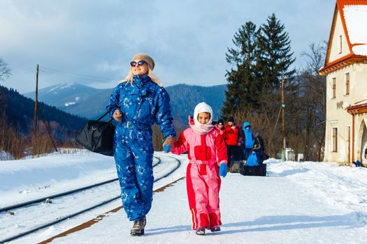 A woman waits with her daughter after heavy snowfall for her train to arrive