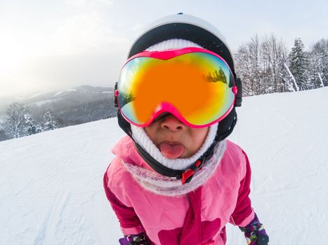 Child skiing in mountains. Active toddler kid with safety helmet, goggles. Winter sport for family