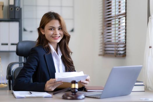 Attractive young lawyer in office Business woman and lawyers discussing contract papers with brass scale on wooden desk in office. Law, legal services, advice, Justice and real estate concept...