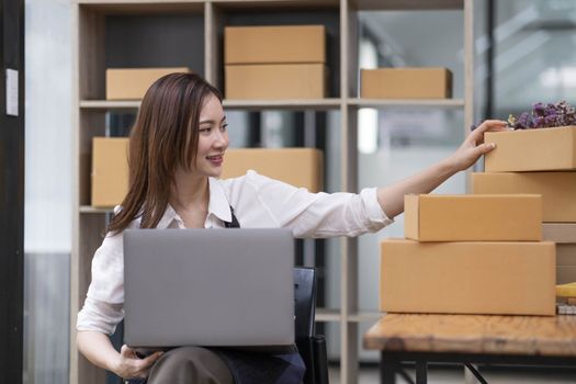 A portrait of a small startup, an SME owner, an Asian female entrepreneur checking orders to arrange the produce before packing the products in the inner boxes with the customers. Freelance concepts..