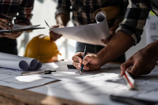 Architect team working with blueprints for architectural plan, engineer sketching a construction project, green energy concept.