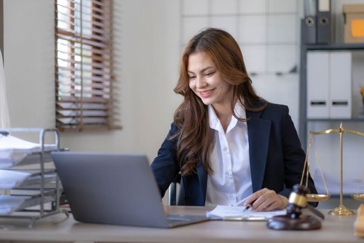 Attractive young lawyer in office Business woman and lawyers discussing contract papers with brass scale on wooden desk in office. Law, legal services, advice, Justice and real estate concept...