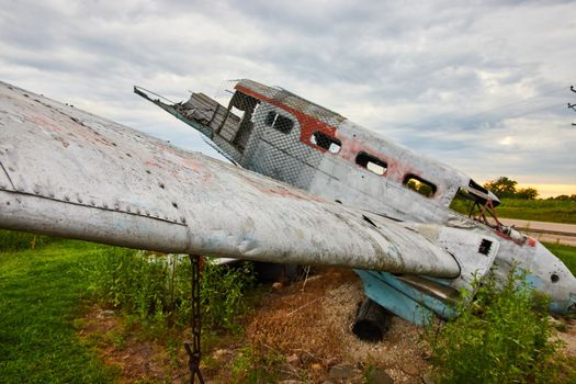 Image of Cloudy day looking at destroyed airplane in field with focus on wing