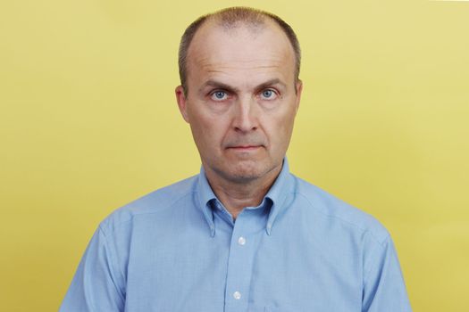 A man in a blue shirt on a yellow paper background.