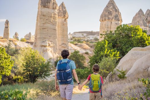 Father and son tourists on background of Unique geological formations in Love Valley in Cappadocia, popular travel destination in Turkey. Traveling with children in Turkey concept.