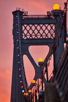 Image of Orange lights in detail on support wires of American bridge with golden light behind