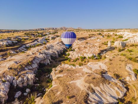 Colorful hot air balloons flying over at fairy chimneys valley in Nevsehir, Goreme, Cappadocia Turkey. Spectacular panoramic drone view of the underground city and ballooning tourism. High quality.