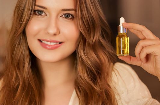 Beautiful woman holding organic oil serum bottle and smiling, evening beauty and skincare routine.