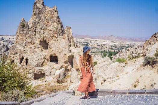 Young woman exploring valley with rock formations and fairy caves near Goreme in Cappadocia Turkey.