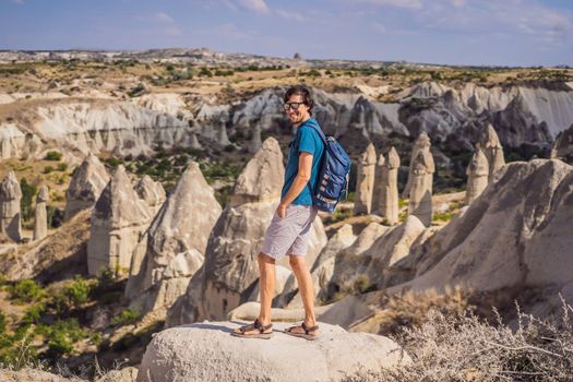 Young man exploring valley with rock formations and fairy caves near Goreme in Cappadocia Turkey.