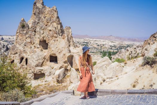 Young woman exploring valley with rock formations and fairy caves near Goreme in Cappadocia Turkey.