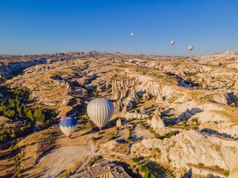 Colorful hot air balloons flying over at fairy chimneys valley in Nevsehir, Goreme, Cappadocia Turkey. Spectacular panoramic drone view of the underground city and ballooning tourism. High quality.