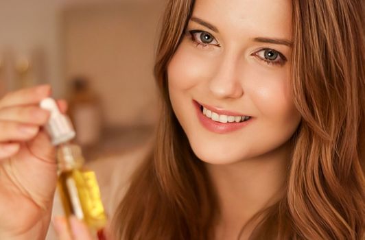 Beautiful woman holding organic oil serum bottle and smiling, evening beauty and skincare routine.