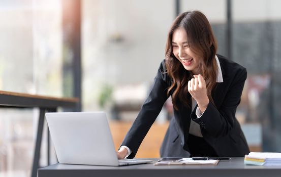 Beautiful asian woman using laptop computer, exciting and celebrating with good news of business successful. Small business startup concept...
