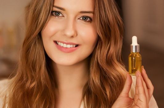 Beautiful woman holding organic oil serum bottle and smiling, evening beauty and skincare routine.
