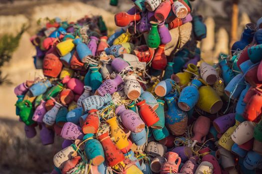 Wish tree. Small multi-colored jugs with inscriptions, wishes hanging on the branches of a tree., against the backdrop of sand ruins and blue sky.